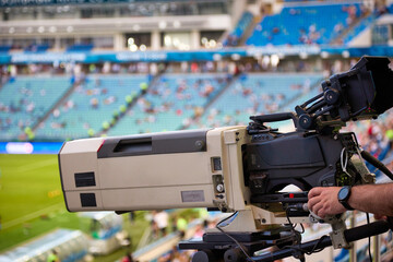 Close-up of a professional television camera in a football stadium, controlled by the hand of a...