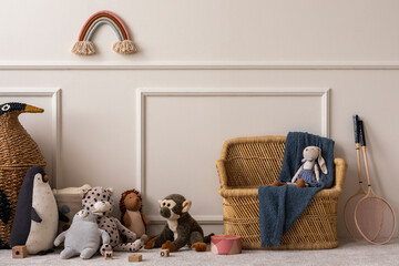 Creative composition of kids room interior with wicker basket, plush animal toys, plaid, wooden...
