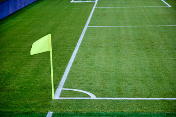 Obraz premium On right corner of the football field there is a green flag on the flagpole. Corner flag as a special element of marking is used by the referee of the match on football with insufficient visibility