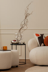 Minimalist composition of living room interior with round coffee table, glass vase with branch,...
