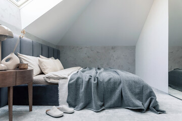 Minimalistic bedroom interior with grey bed, beige bedclothes, wooden night table and elegant...