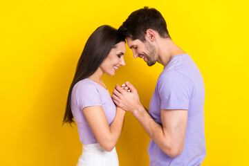 Profile photo of two lovely positive people closed eyes hold hands touch heads isolated on yellow color background