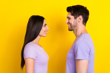 Profile photo of two satisfied glad people beaming smile look each other isolated on yellow color...