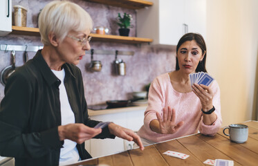 Asian elderly woman showing stop gesture while playing cards with friend