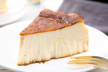 明るいテーブルにバスクチーズケーキと金色のフォーク