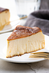 明るいテーブルにバスクチーズケーキと金色のフォーク