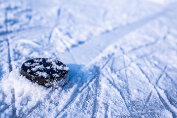 black hockey puck lies on ice at stadium