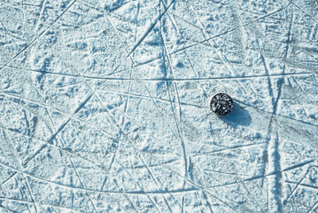black hockey puck lies on ice at stadium