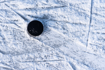 black hockey puck lies on ice at stadium