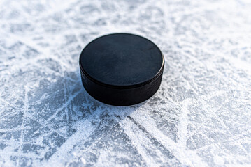 black hockey puck lies on ice at stadium