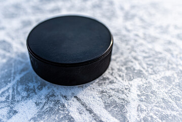 black hockey puck lies on ice at stadium