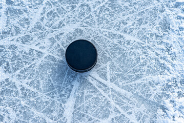 black hockey puck lies on ice at stadium