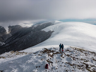 Couple on a small peak contemplating the snowy mountains