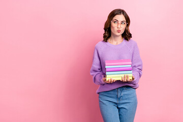 Photo of unsure dreamy girl dressed purple pullover eyewear looking empty space holding book pile isolated pink color background