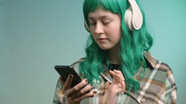 Gen Z, beautiful girl with green hair listening music using subscription service.