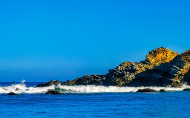 Beautiful rocks cliffs surfer waves at beach Puerto Escondido Mexico.