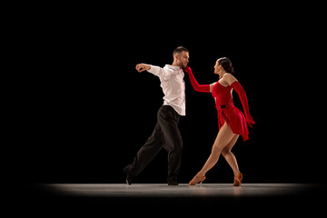 Tender, romantic, passionate dance. Young man and woman dancing tango, ballroom over black background. Concept of hobby, lifestyle, action, beauty of movements, emotions, fashion, art