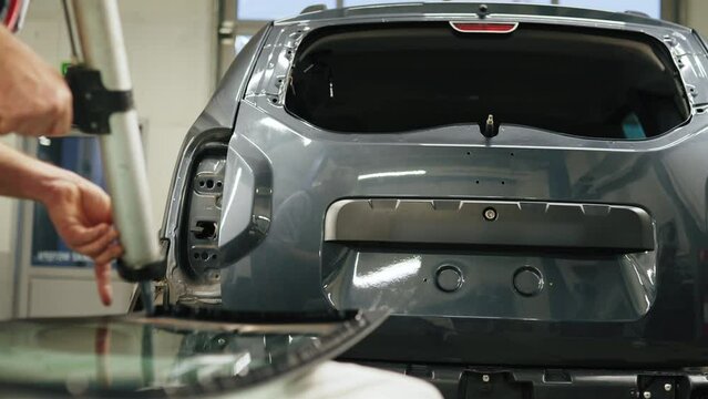 Mechanic adding glue to the windscreen of a car windshield replacement station. High-quality 4k footage