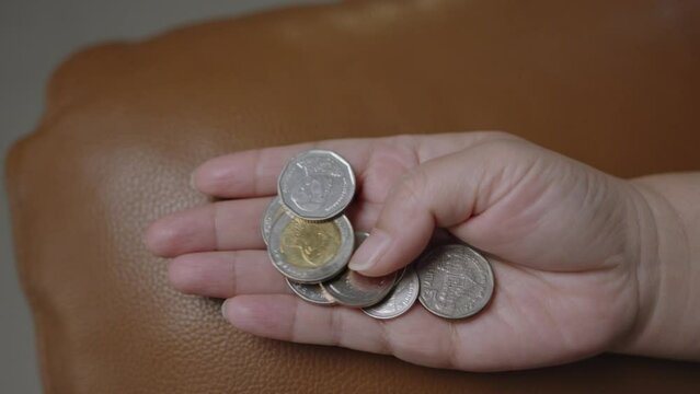 Thai baht coins in female hand first person point of view shot. THB is official currency of Thailand.