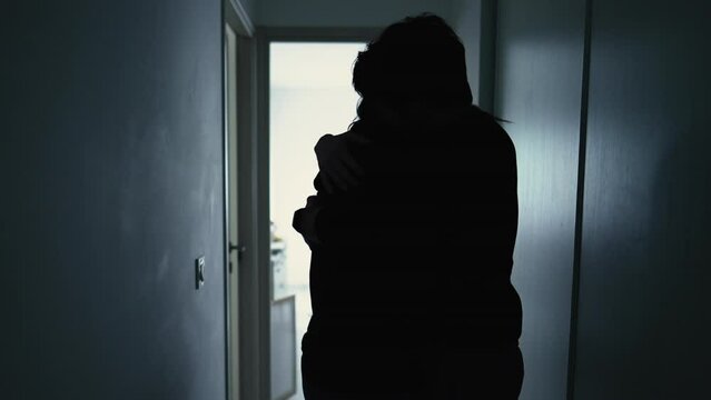 Couple making peace after fight. Husband hugging whife showing support and love. Caring relationship standing in silhouette in apartment corridor