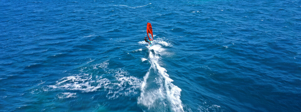 Aerial drone ultra wide photo with copy space of wind athlete surfer competing among others in deep blue open ocean sea © aerial-drone