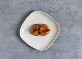 Two coconut cookies on a plate. Top view.