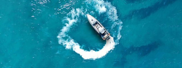 Obraz na płótnie Canvas Aerial drone top down ultra wide photo with copy space of inflatable power rib boat making extreme manoeuvres in Mediterranean bay with deep blue sea at dusk