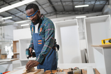 Portrait African American carpenter use electric screwdriver with wood timber at wood factory	