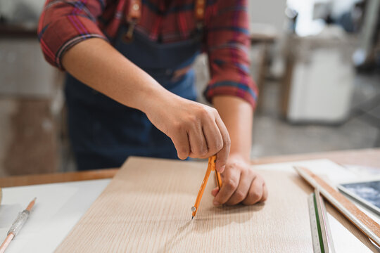 Unknown carpenter use compass math on wood sheet timber at wood factory - Powered by Adobe