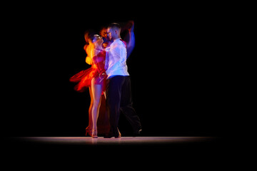 Beautiful young people, man and woman dancing tango, ballroom over black background with mixed neon...