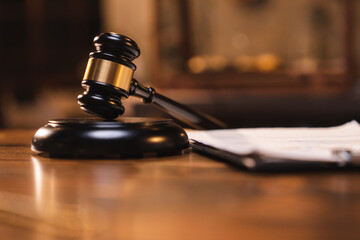 Judge gavel on the table with blurry books in the background