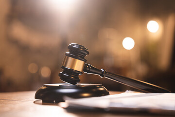 Judge gavel on the table with blurry books in the background
