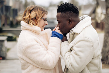 Portrait of young interracial couple holding each other hands on street.
