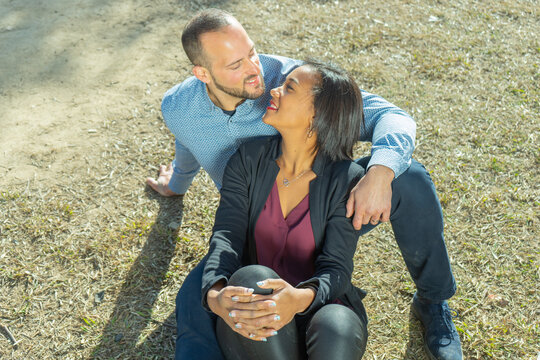 Diverse couple affectionately standing together outside on a sunny day