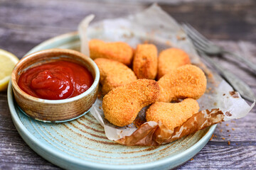 
 Crispy oven baked  chicken nuggets and ketchup. Breaded chicken fillets  with chilly peppers and fresh basi on wooden rustic background