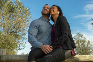 Diverse couple affectionately standing together outside on a sunny day