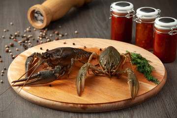 Two fresh crawfish on a wooden cutting board with pepper on the table