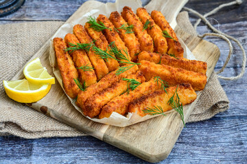 Close up of   Crispy breaded  deep fried fish fingers with breadcrumbs served  with remoulade sauce and  lemon Cod Fish Nuggets on rustic wood table background