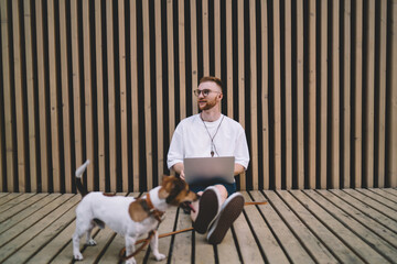 Smiling male freelancer using laptop on street with dog