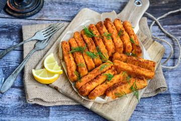 Close up of   Crispy breaded  deep fried fish fingers with breadcrumbs served  with remoulade sauce and  lemon Cod Fish Nuggets on rustic wood table background