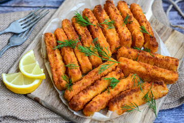 Close up of   Crispy breaded  deep fried fish fingers with breadcrumbs served  with remoulade sauce and  lemon Cod Fish Nuggets on rustic wood table background