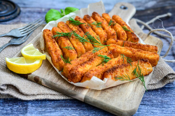 Close up of   Crispy breaded  deep fried fish fingers with breadcrumbs served  with remoulade sauce and  lemon Cod Fish Nuggets on rustic wood table background