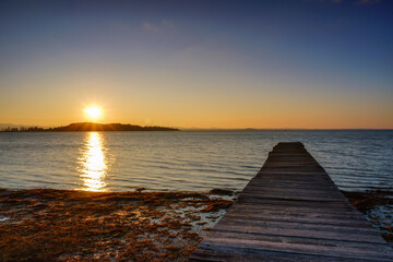 Fototapeta premium Wooden warf over Isola Polvese at the sunset, Trasimeno Lake, Perugia, Umbria, Italy
