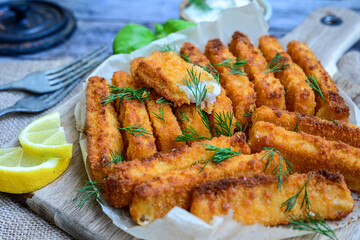 Close up of   Crispy breaded  deep fried fish fingers with breadcrumbs served  with remoulade sauce and  lemon Cod Fish Nuggets on rustic wood table background
