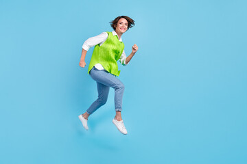 Fototapeta na wymiar Full size photo of pleasant gorgeous girl brown hairdo wear green vest jeans running at sale shopping isolated on blue color background