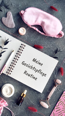Face massage roller, gua sha stone, essential oil, moisturizer, silk mask, night cream. Page in notebook with caption. Text meine gerichtphlege routine means my face care routine in German language