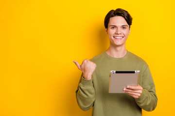 Photo of cheerful nice man wear stylish clothes offer visit new device shop demonstrate empty space isolated on yellow color background