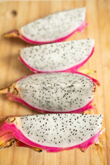 exotic dragon fruit of pink color, cut in half, on a wooden board. Weight loss, proper nutrition, diet, expensive fruits, slicing. Allergic to exotic.