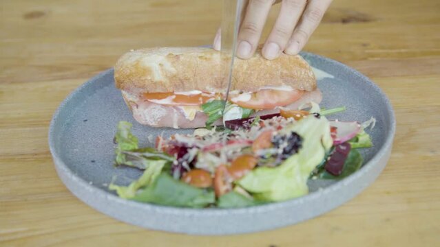 Plano a detalle de emparedado de jam&oacute;n acompa&ntilde;ado de ensalada, queso, aderezo, vegetales sobre mesa