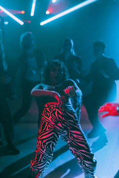 Young woman bending backwards while dancing against friends at nightclub enjoying weekend